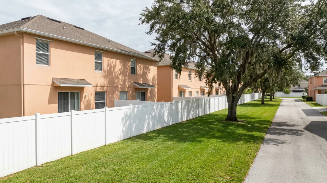Illustrative image: a white vinyl privacy fence along a grassy backyard