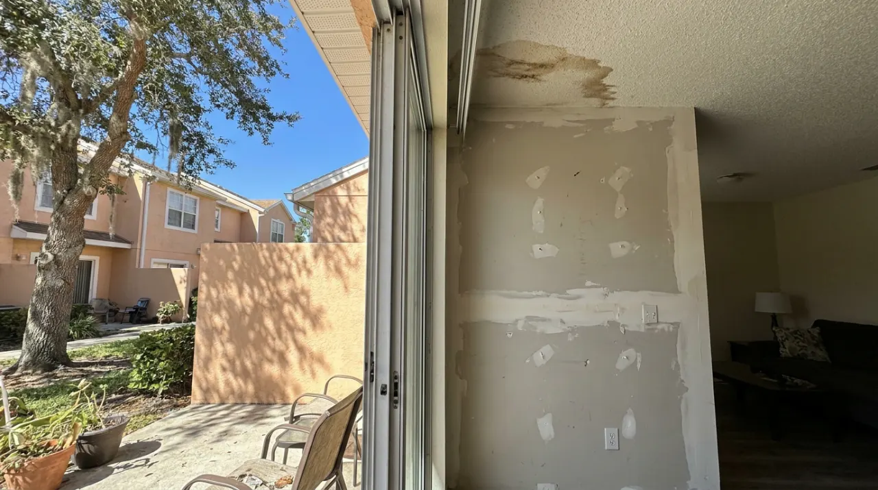 A poorly finished drywall wall with lumpy tape seams, nail pops and a water stain on the ceiling.